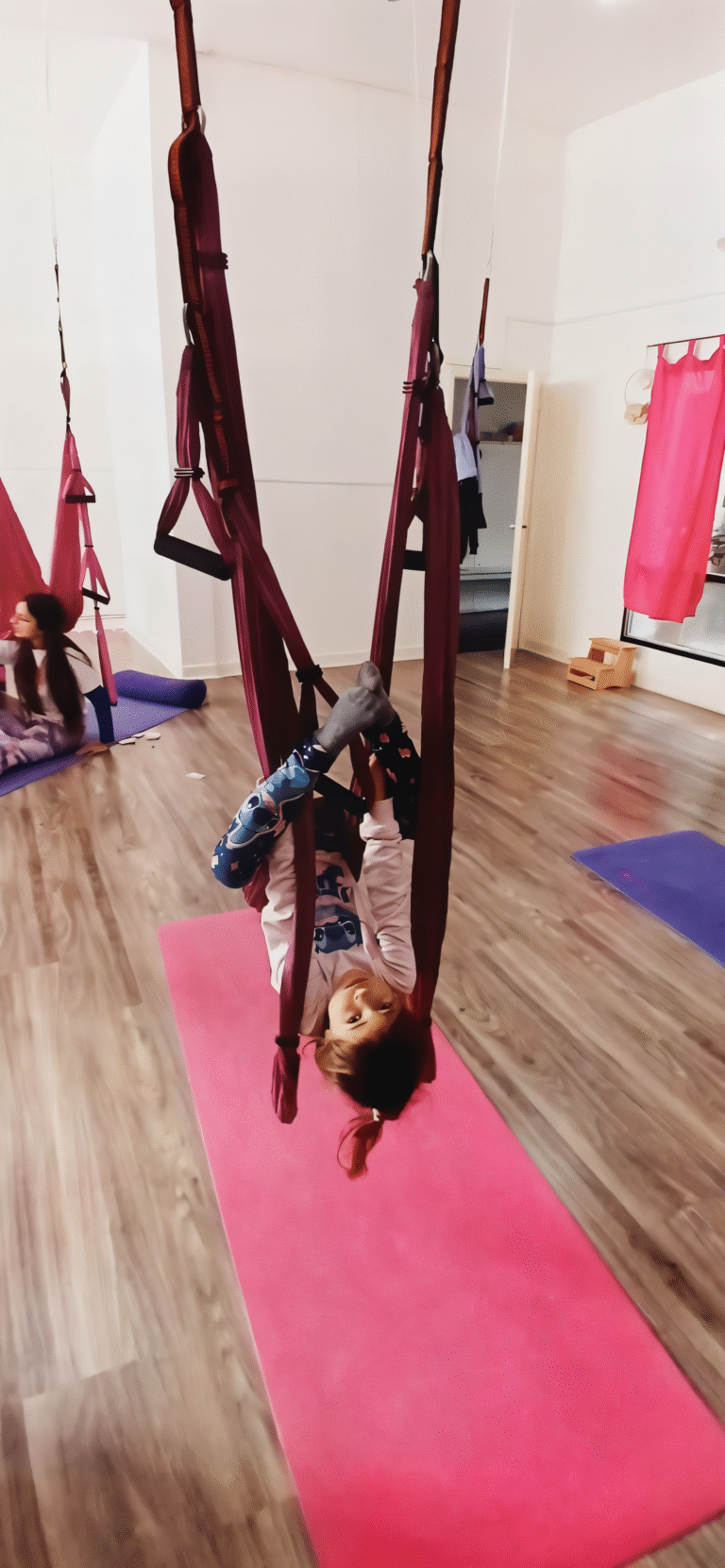 Child hanging upside down in kids aerial yoga hammock at YogaAereo Browns Bay Auckland.